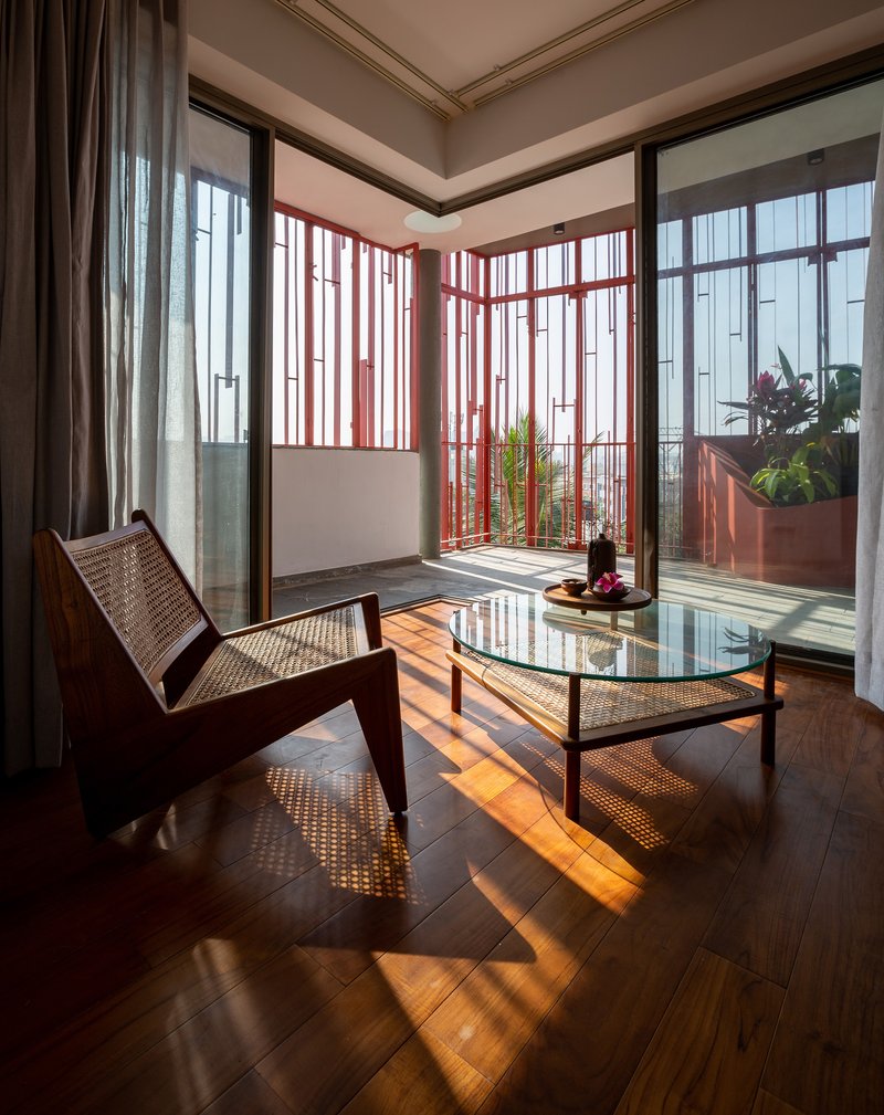 Interior living space with cane chairs and striped sunlight patterns from the red batten enclosure