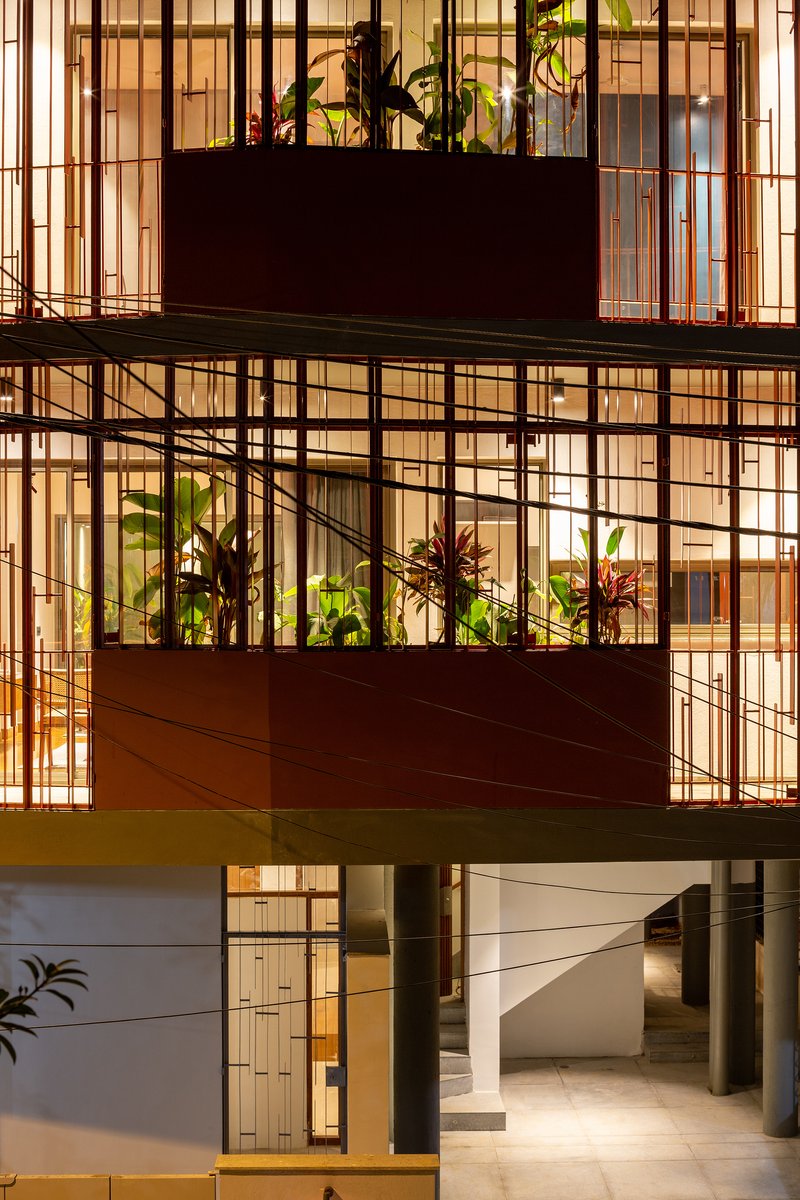 Close-up of the tiered balconies with metal grid enclosures and tropical plantings at dusk