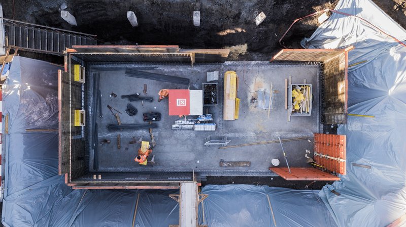 Overhead view of concrete slab during construction with workers and protective tarps