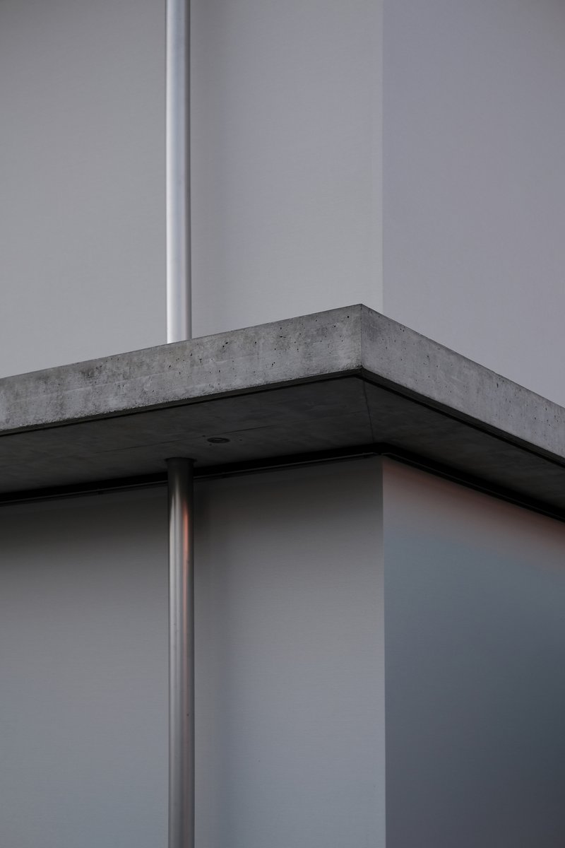 Close-up of concrete beam corner supported by steel column with recessed black soffit panel