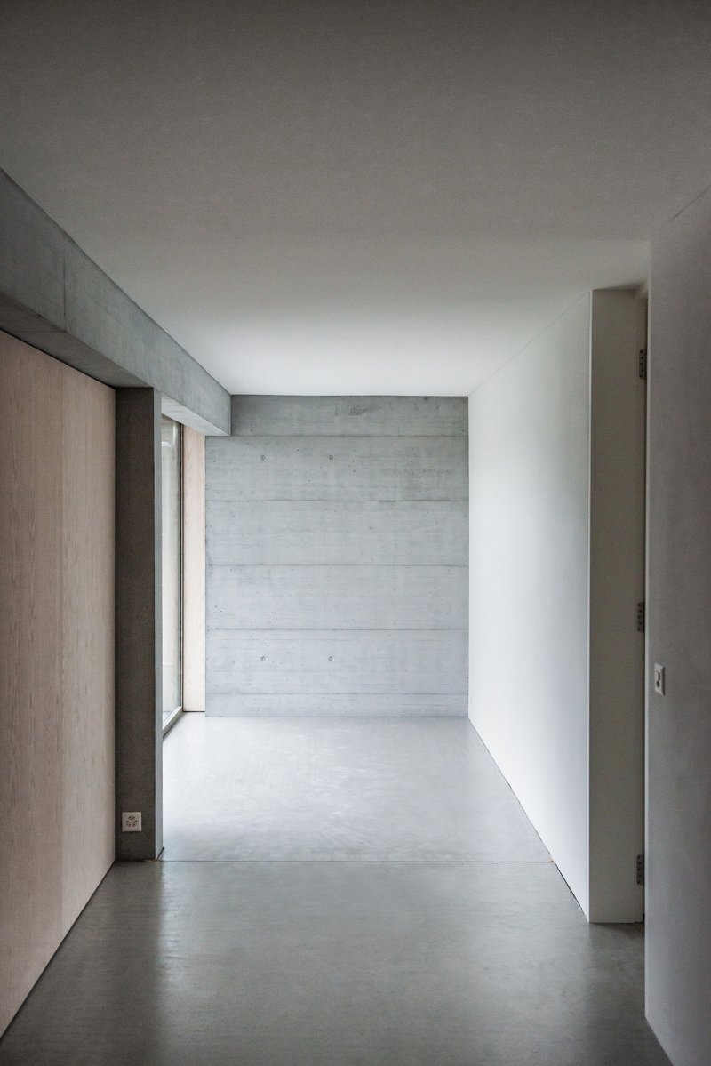 Interior corridor with board-formed concrete end wall and light oak wood panels along one side
