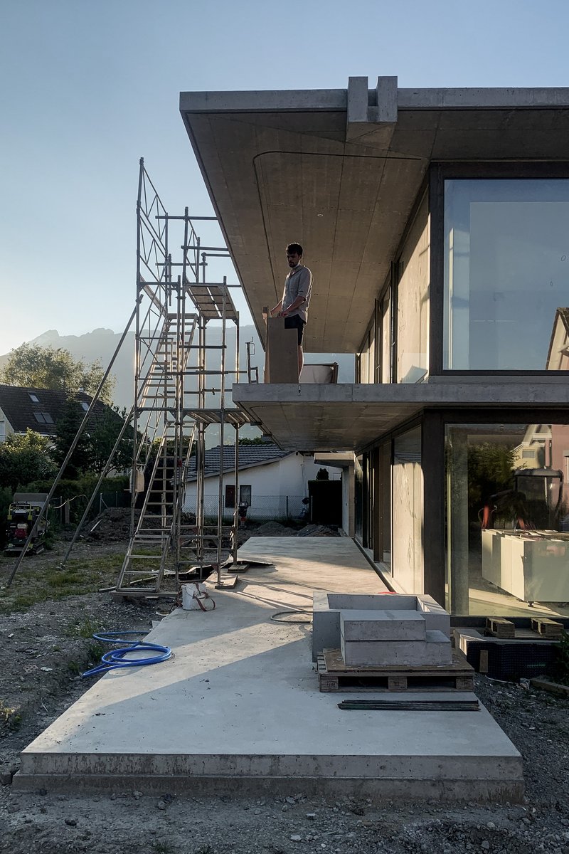 Concrete cantilever terrace with scaffolding and figure standing in late afternoon light