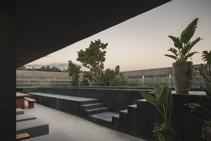 Rooftop terrace with dark concrete stepped seating and planters under an overcast sky