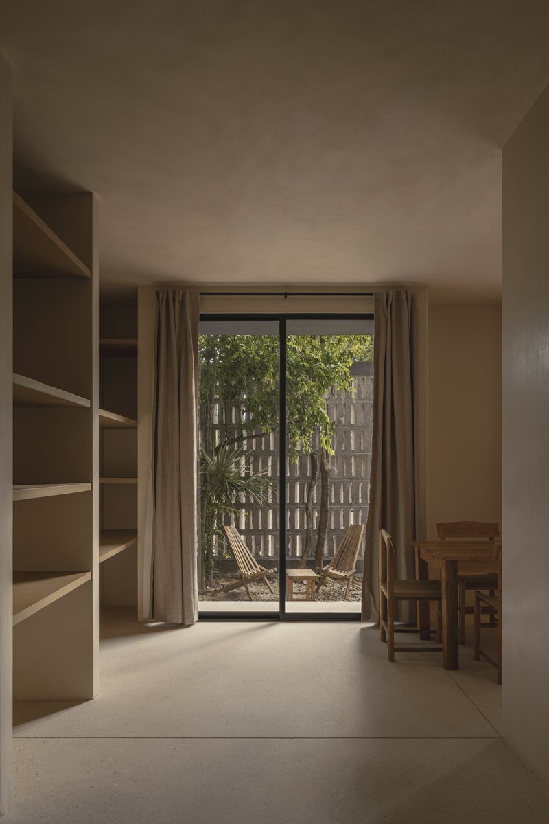 Interior room with built-in shelving and glazed doors opening to planted courtyard with block screen wall