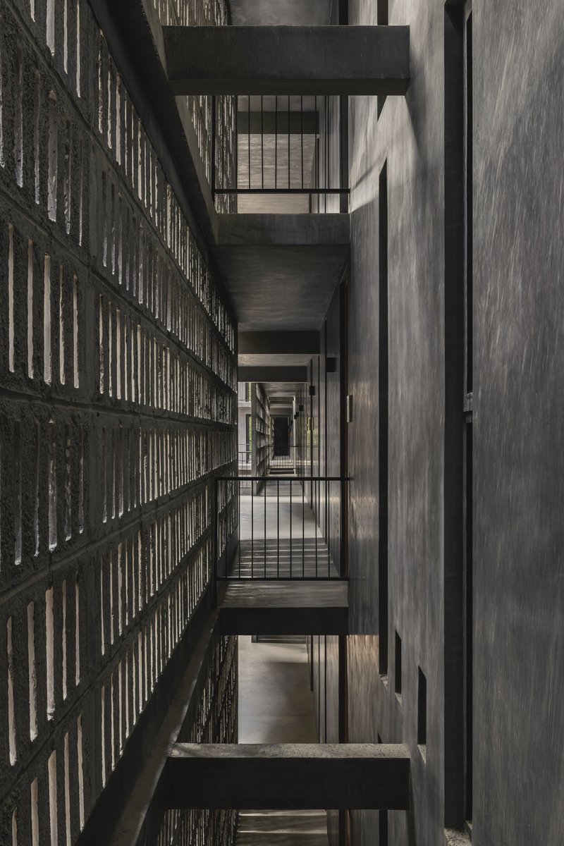 Vertical view through the stairwell showing alternating concrete bridges and perforated brick screen walls