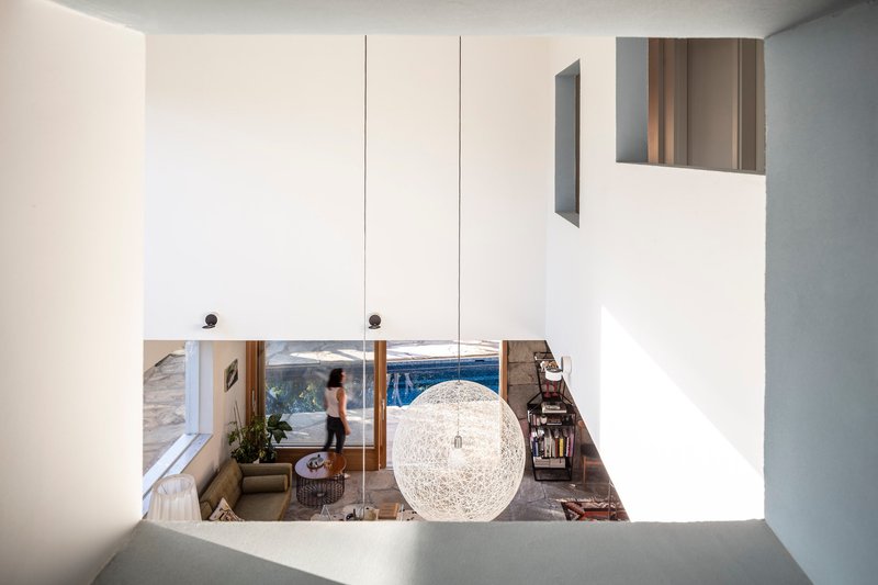 View down from upper level through void showing spherical pendant light and figure in living space below