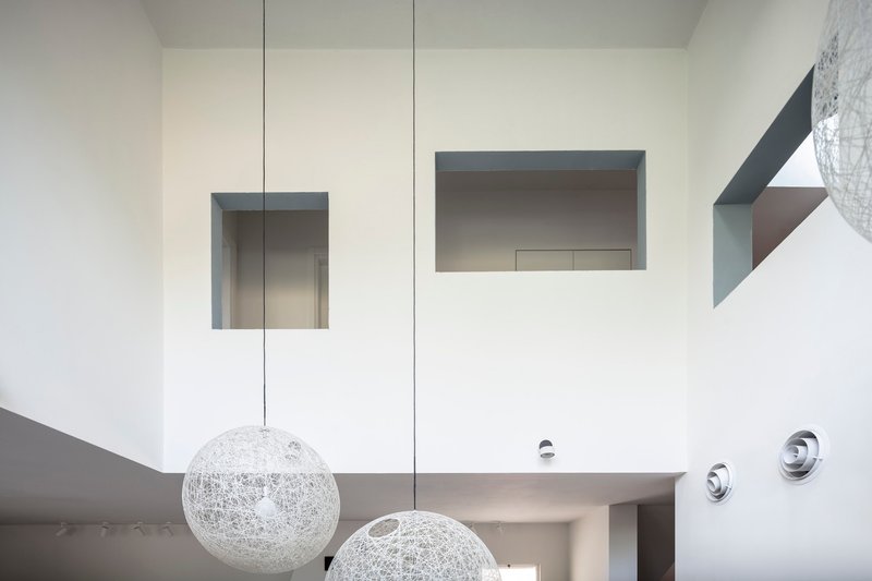 Double-height void with recessed wall niches and wire sphere pendants suspended below