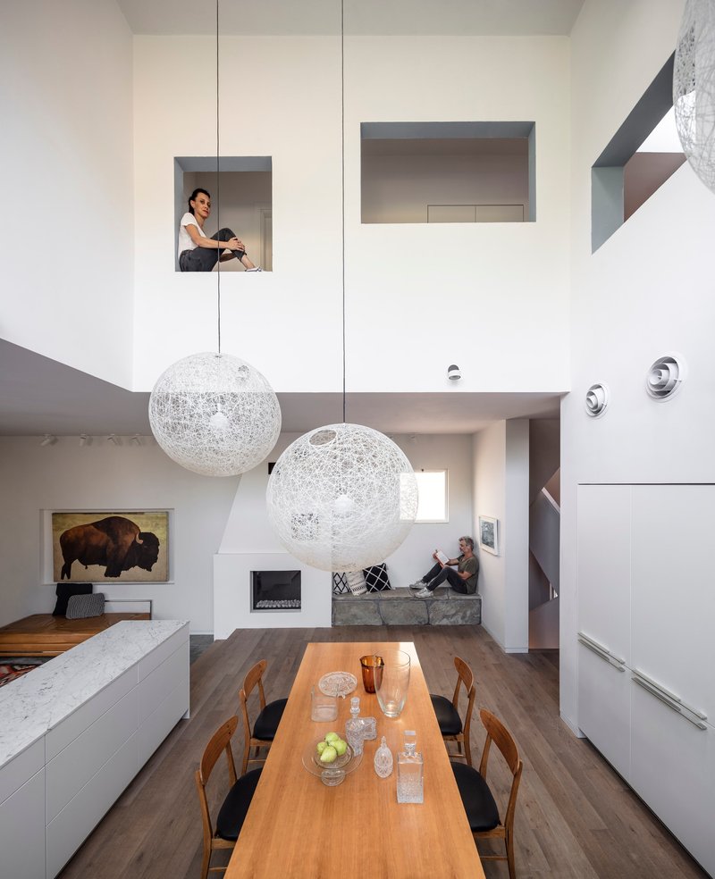 View across the dining table toward niches and a seated figure in the upper-level opening