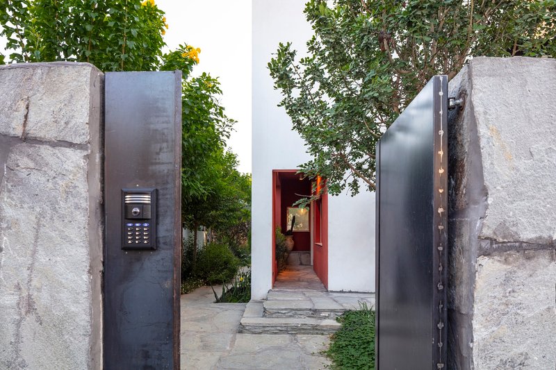 Entry gate with steel panels set between rough stone piers and view to red threshold