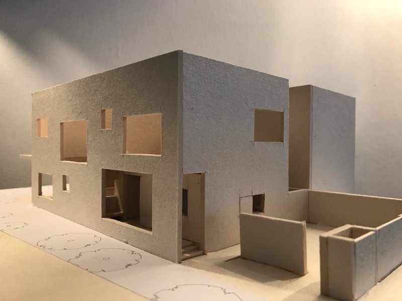 Physical model showing the street facade with entry courtyard and stepped massing under dramatic lighting