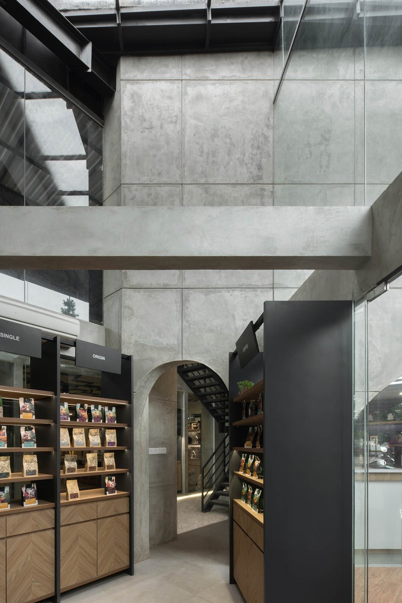 Interior view of concrete beams and arch framing the retail shelving and steel staircase