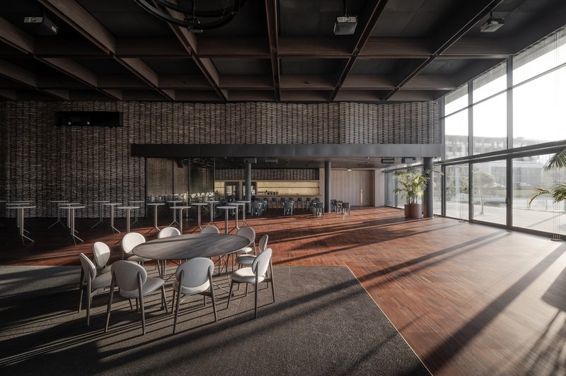 Dining area with exposed timber ceiling beams and floor-to-ceiling windows casting afternoon shadows across hardwood flooring