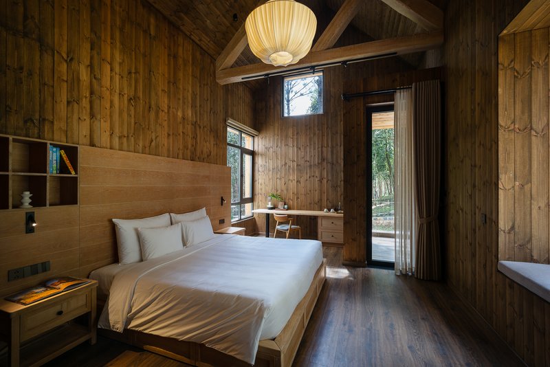 Bedroom with timber-clad walls, built-in desk, and glass doors opening to exterior courtyard