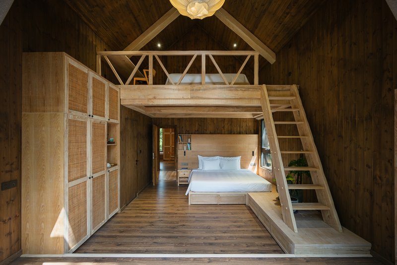 Bedroom with timber loft platform accessed by a ladder beneath an exposed wood rafter ceiling