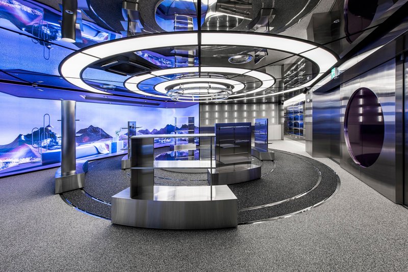 Interior showroom with circular counter below concentric ceiling rings and purple lighting