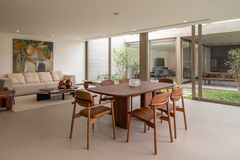 Open-plan dining and living area with timber table, terrazzo flooring, and views to planted courtyards