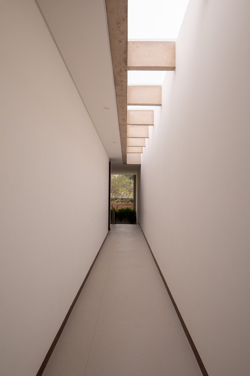Narrow corridor with clerestory skylight slots and a view through to the garden
