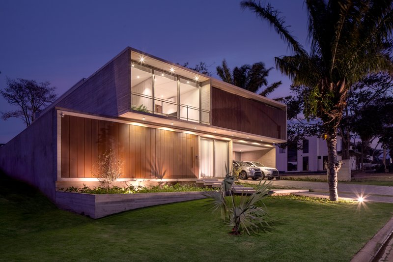 Street facade with vertical wood cladding and planted plinth under a purple evening sky