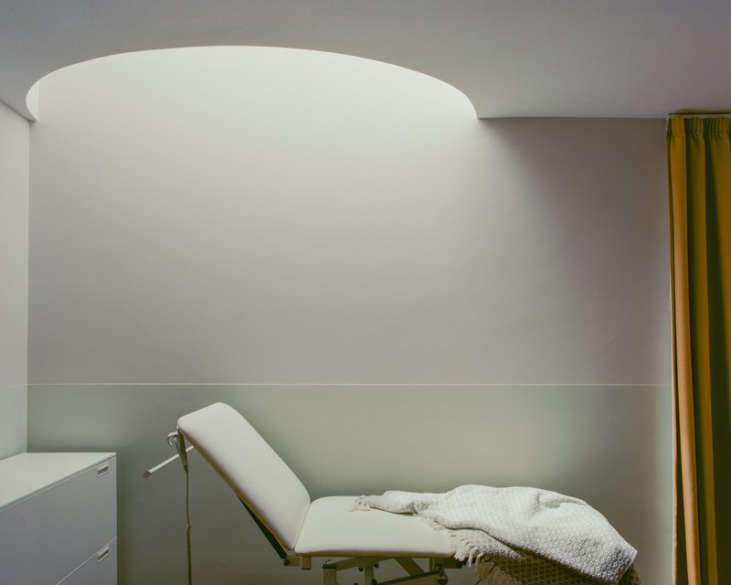 Interior treatment room with curved white ceiling and reclined chair beneath soft ambient light