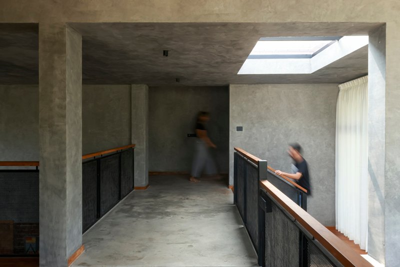 Upper level corridor with concrete ceiling and skylight illuminating two figures in motion