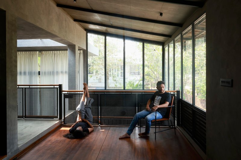Timber floor study room with concrete ceiling beams and two occupants by glazed wall