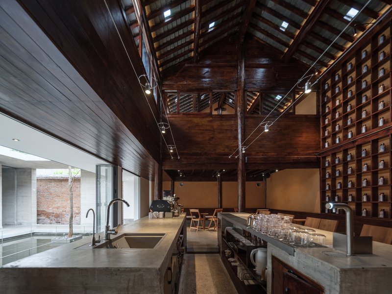 Refurbished timber pavilion interior with exposed trusses and skylights above stainless steel cafe counter