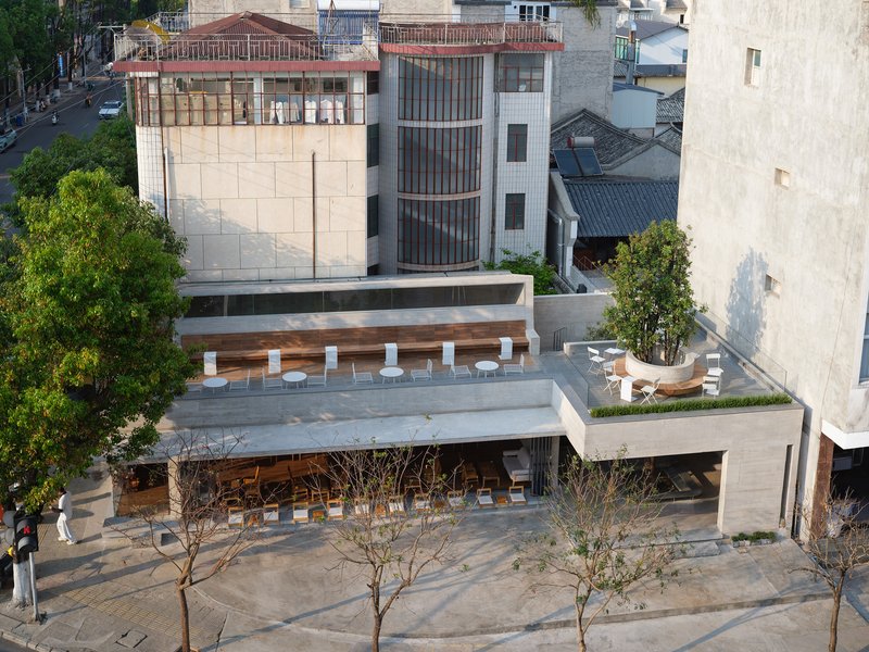 Aerial view of tiered concrete terraces with timber louvers and rooftop seating among bare winter trees