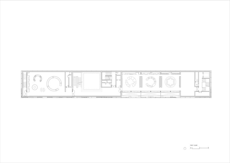 Floor plan drawing showing a long narrow volume with circular meeting spaces and rows of workstations