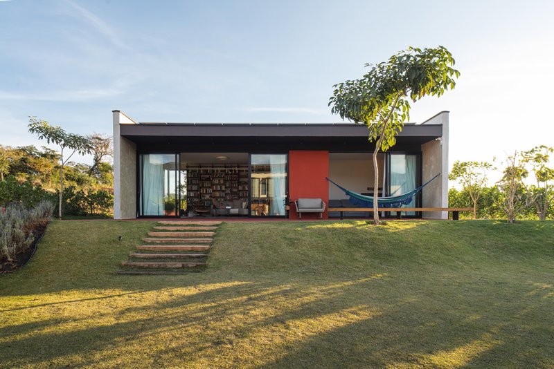 Garden facade with concrete butterfly roof and glazed walls framing interior views at dusk