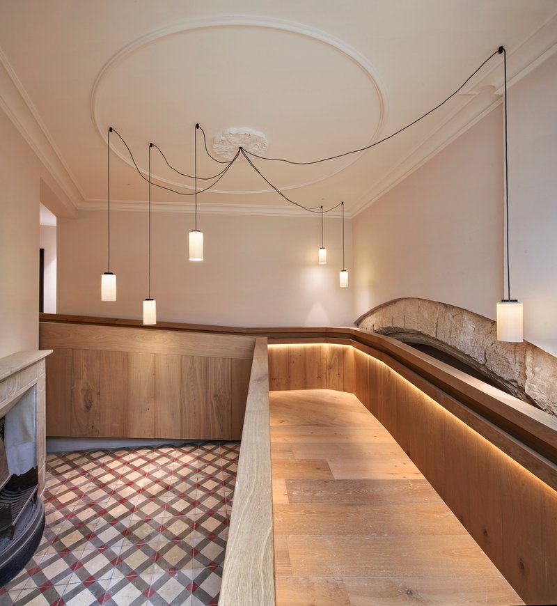 Curved timber bench with integrated lighting below pendant fixtures and a circular ceiling medallion