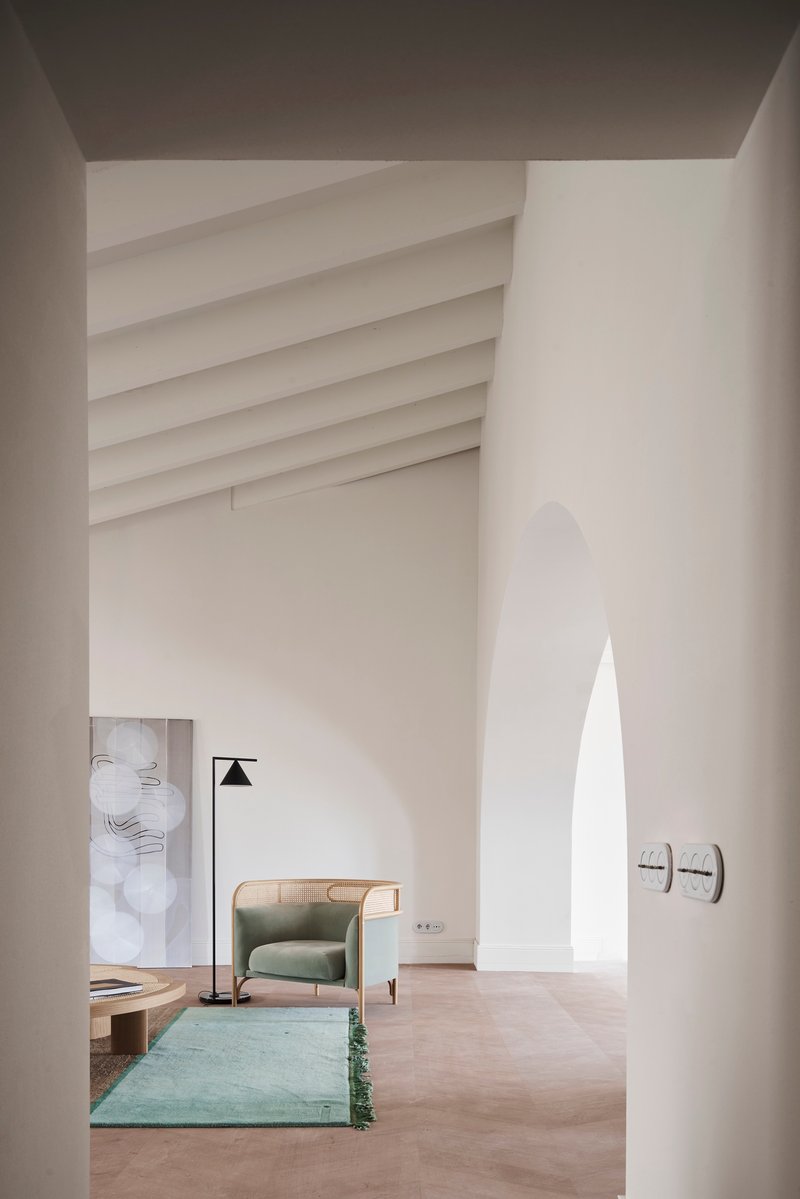 View through arched opening into a double-height space with ribbed vaulted ceiling and pale plaster walls