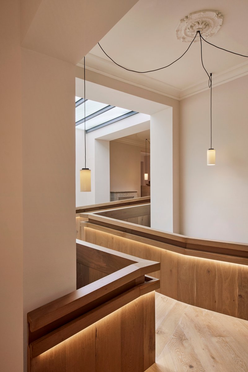 View through doorway to timber pews with integrated strip lighting and pendant fixtures below ceiling rosette