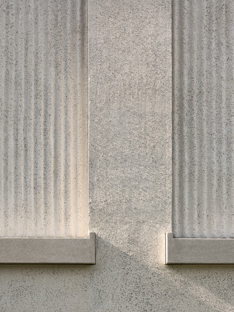 Close-up of vertically fluted concrete panels meeting at a corner joint in bright sunlight
