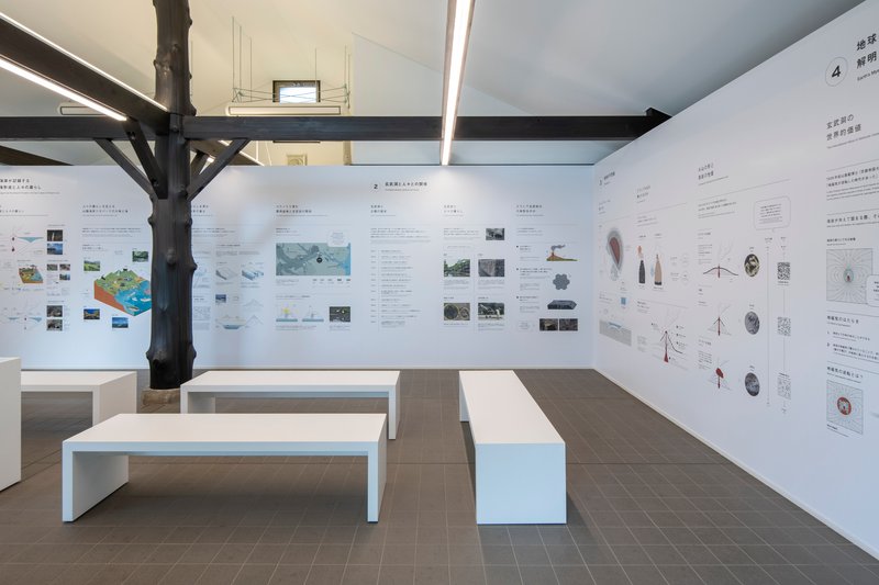 Gallery interior with white display panels on walls, white benches, and exposed timber columns