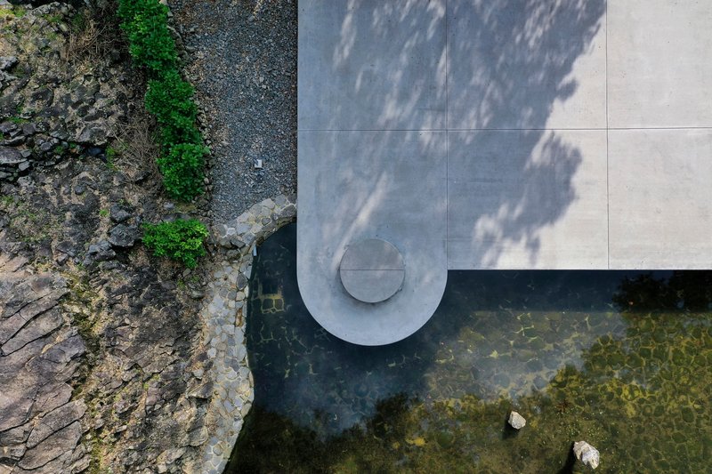 Overhead view of the concrete cantilever with circular vent extending over dark quarry water