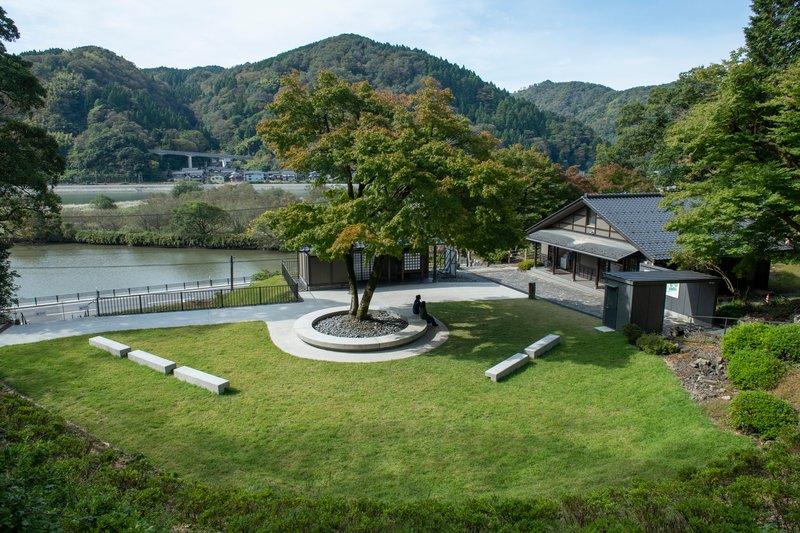 Overview of the lawn with circular tree planting and concrete benches overlooking a river valley