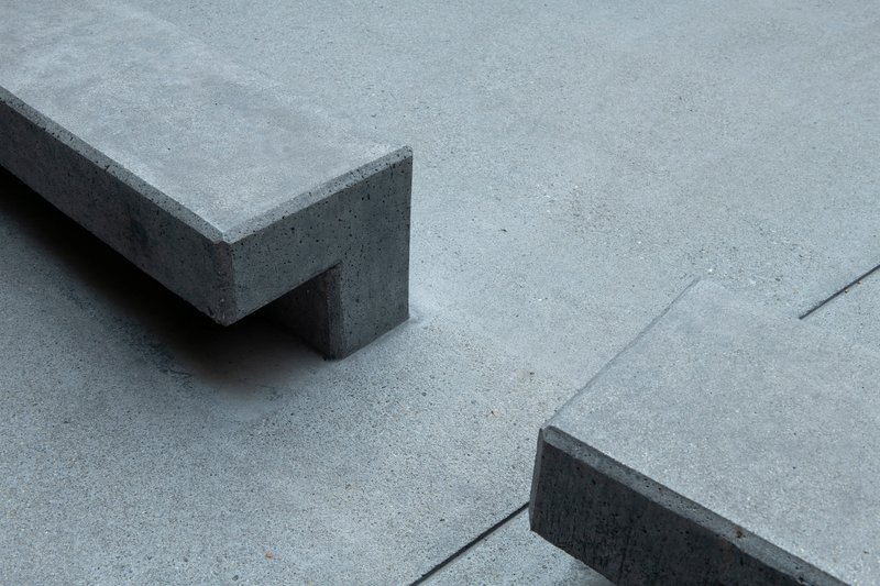 Detail of concrete bench corner casting shadow on poured concrete plaza surface
