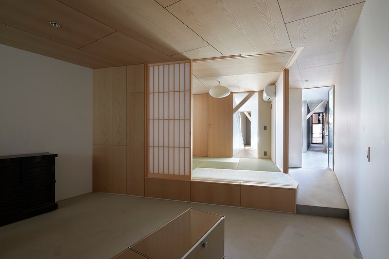 Interior room with plywood ceiling and raised tatami platform behind translucent shoji screen