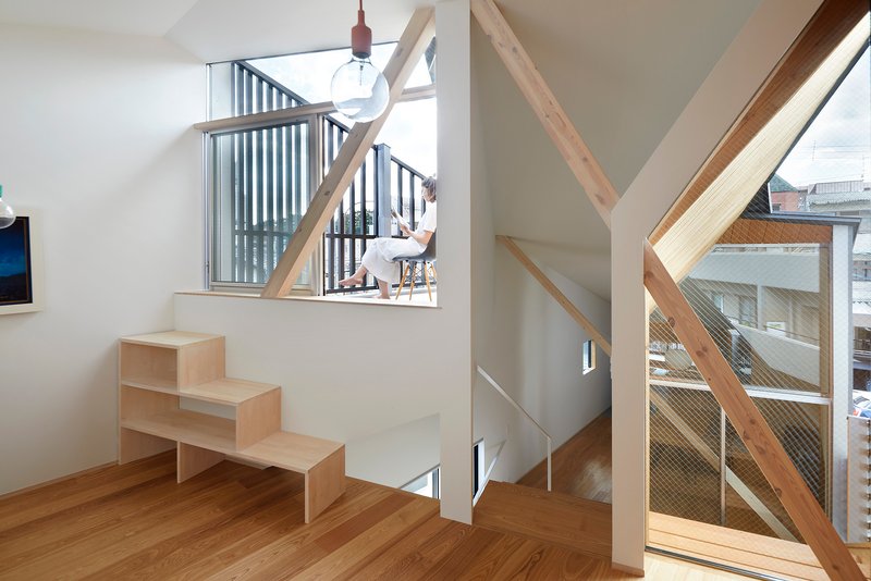 Upper level corridor with plywood shelving unit and diagonal timber bracing framing wire mesh balustrades