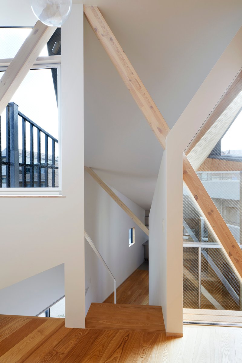 Angular stairwell with exposed timber rafters and white walls meeting at faceted ceiling planes