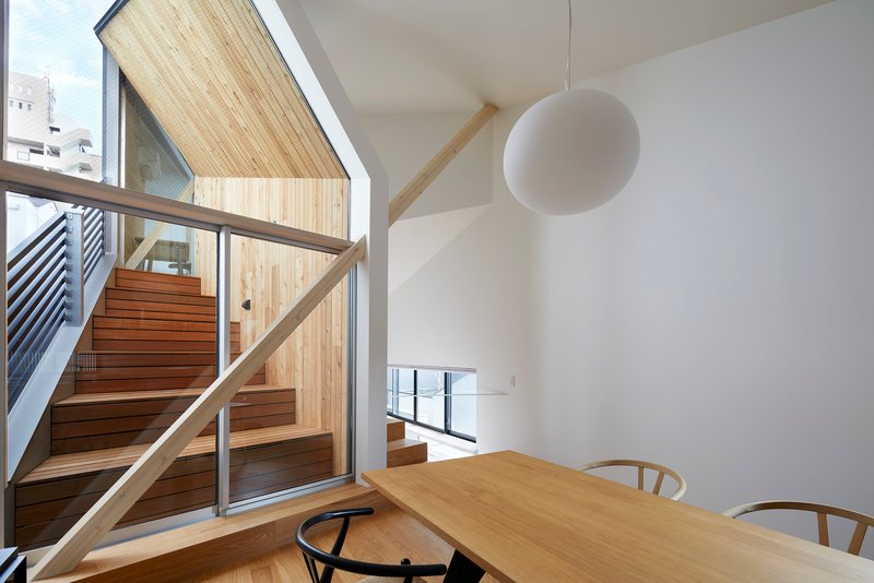 Dining area with timber table and glazed wall opening to external timber stair and metal balcony