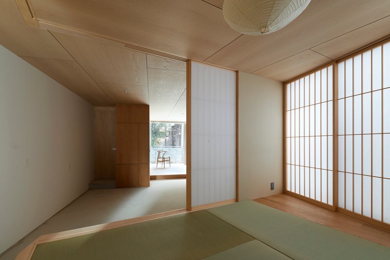 Tatami mat room with translucent shoji screen wall and plywood ceiling with paper pendant light