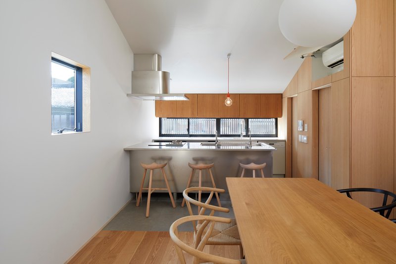 Open kitchen and dining area with timber cabinetry and three wooden stools at the counter