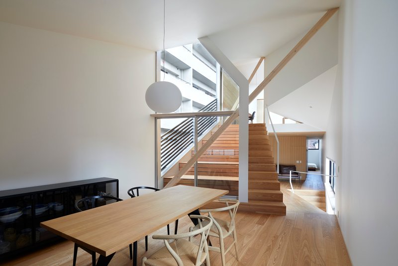 Open staircase with timber treads and diagonal metal railing connecting dining area to upper levels