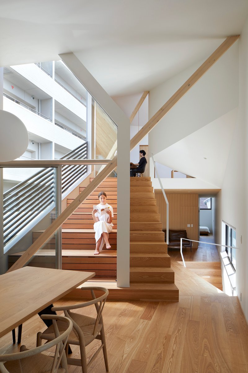Multi-level timber staircase with diagonal striped railings where two people sit on the steps