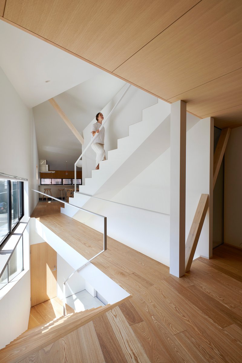 White painted staircase ascending between plywood ceiling panels and exposed timber diagonal bracing