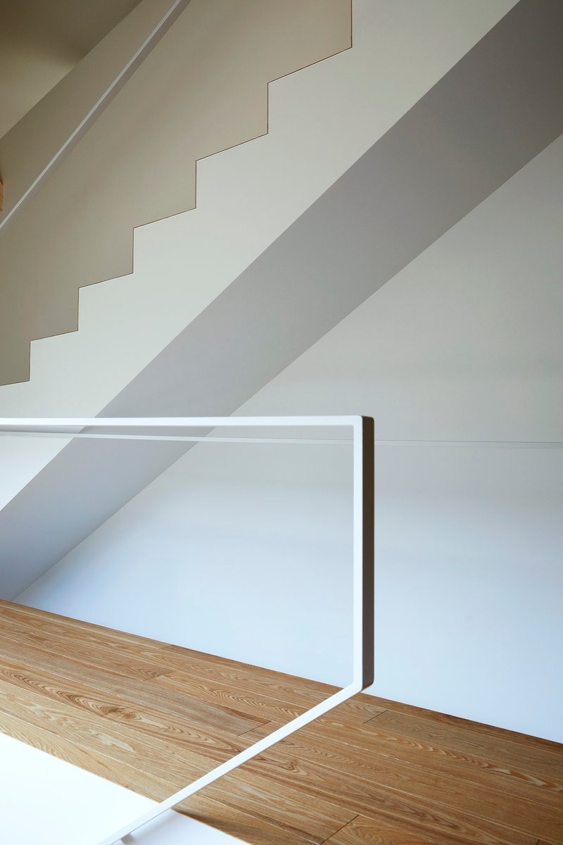 White staircase wall with shadow patterns cast by the railing and natural light