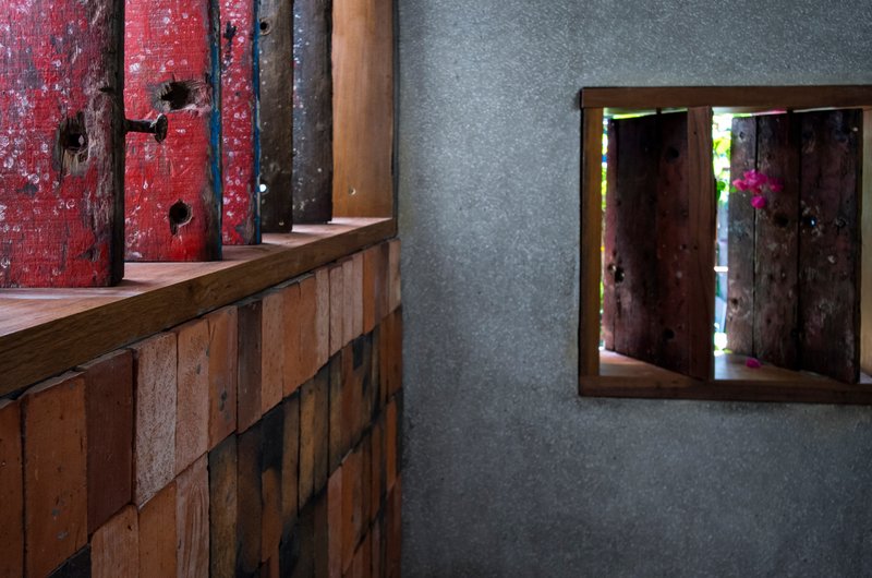 Interior counter with reclaimed timber cladding next to framed window opening in concrete wall