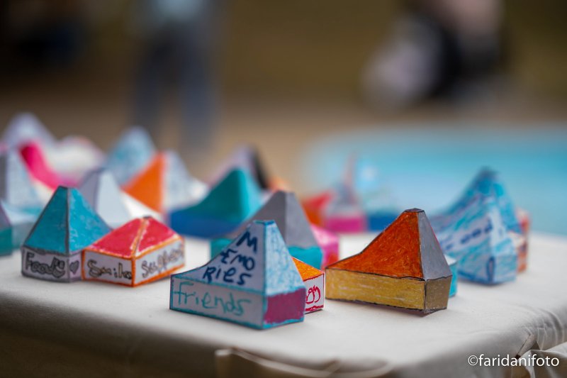 Colorful paper models with pyramidal roofs arranged on a white surface with handwritten labels