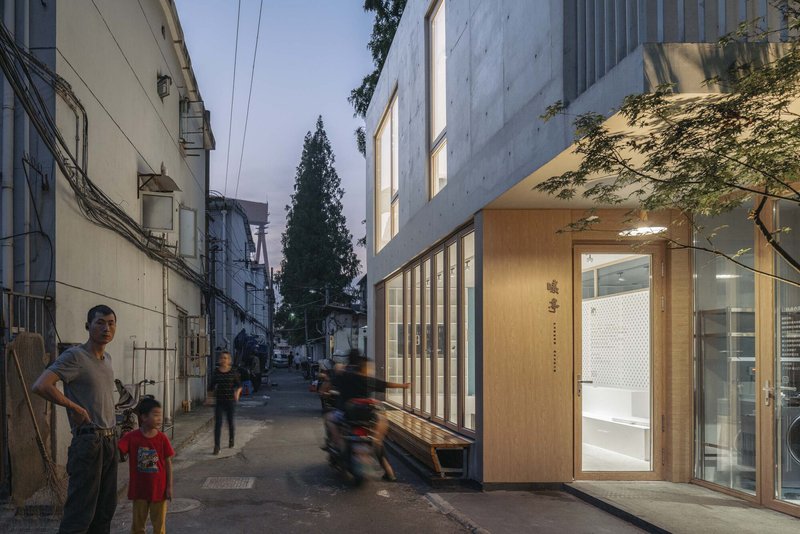 Narrow alley view of the timber-framed entrance with pedestrians and bicycles passing by at twilight